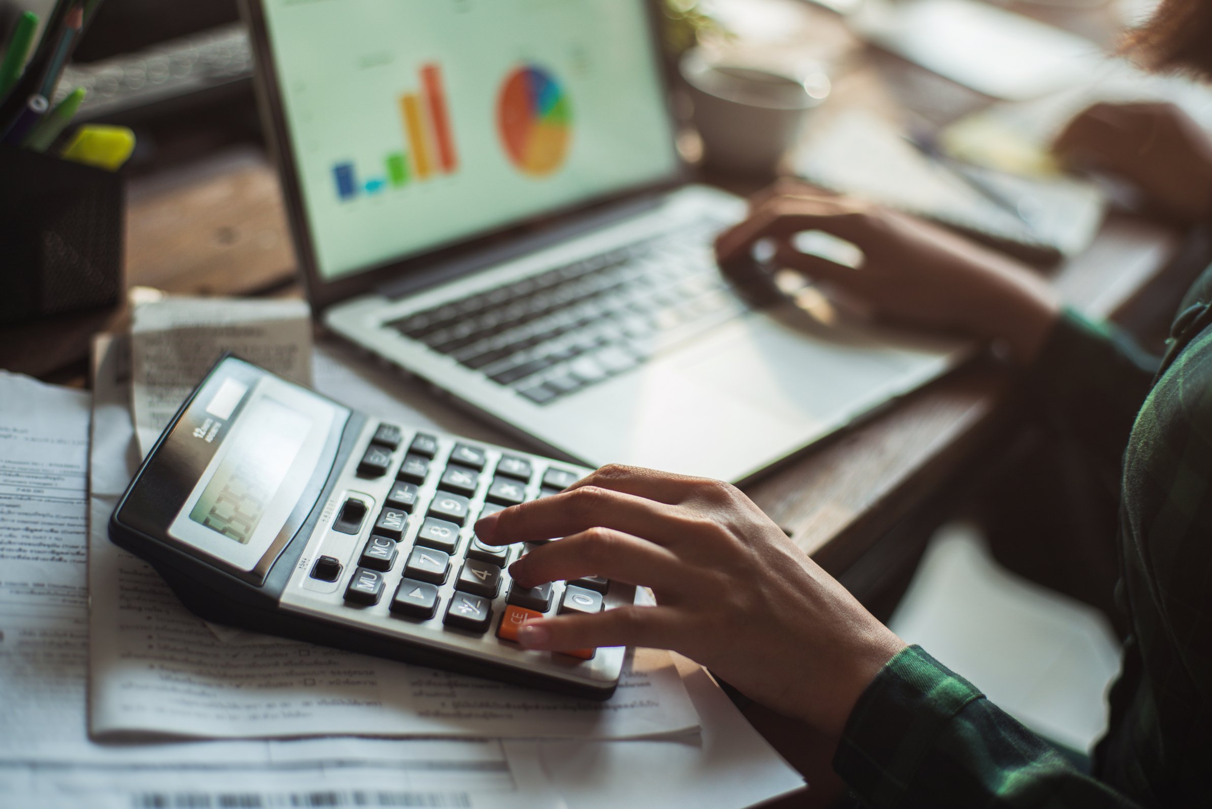 Woman is calculating the cost of the bill. She is pressing the calculator.